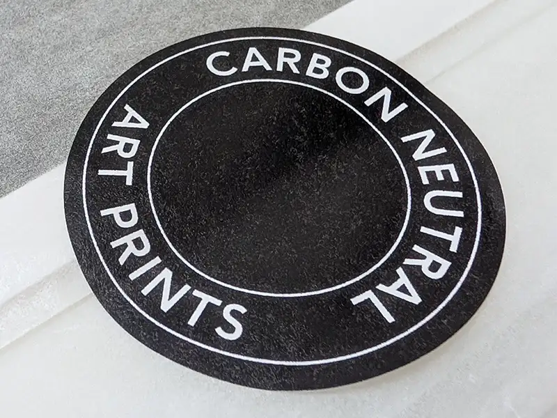 Round 'Carbon Neutral Art Prints' label on black by Botanographia