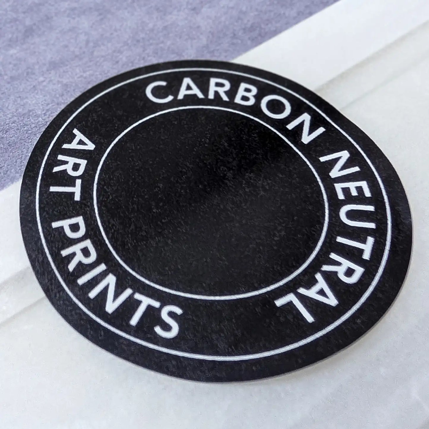 Round 'Carbon Neutral Art Prints' label on black by Botanographia