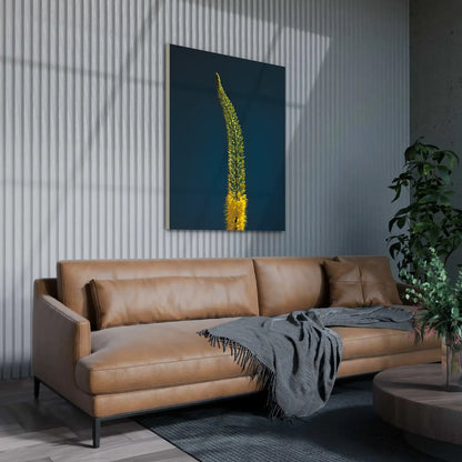 A lifestyle image for representation only showing a light brown pleather sofa, grey rug, grey throw, grey strip panel wall featuring a bright yellow foxtail lily photographic print with an intense blue-y green background.